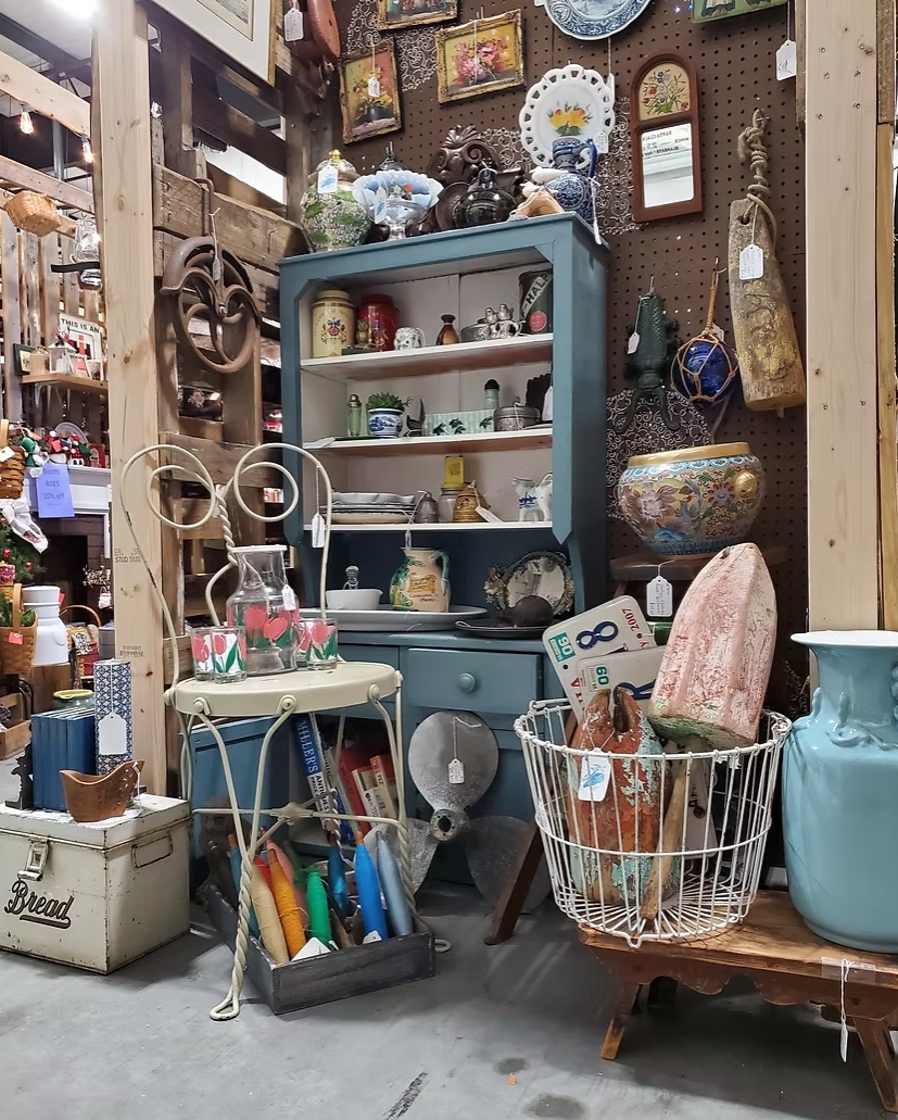 A display of vintage finds with a blue cabinet, ceramics, glassware, and coastal collectibles